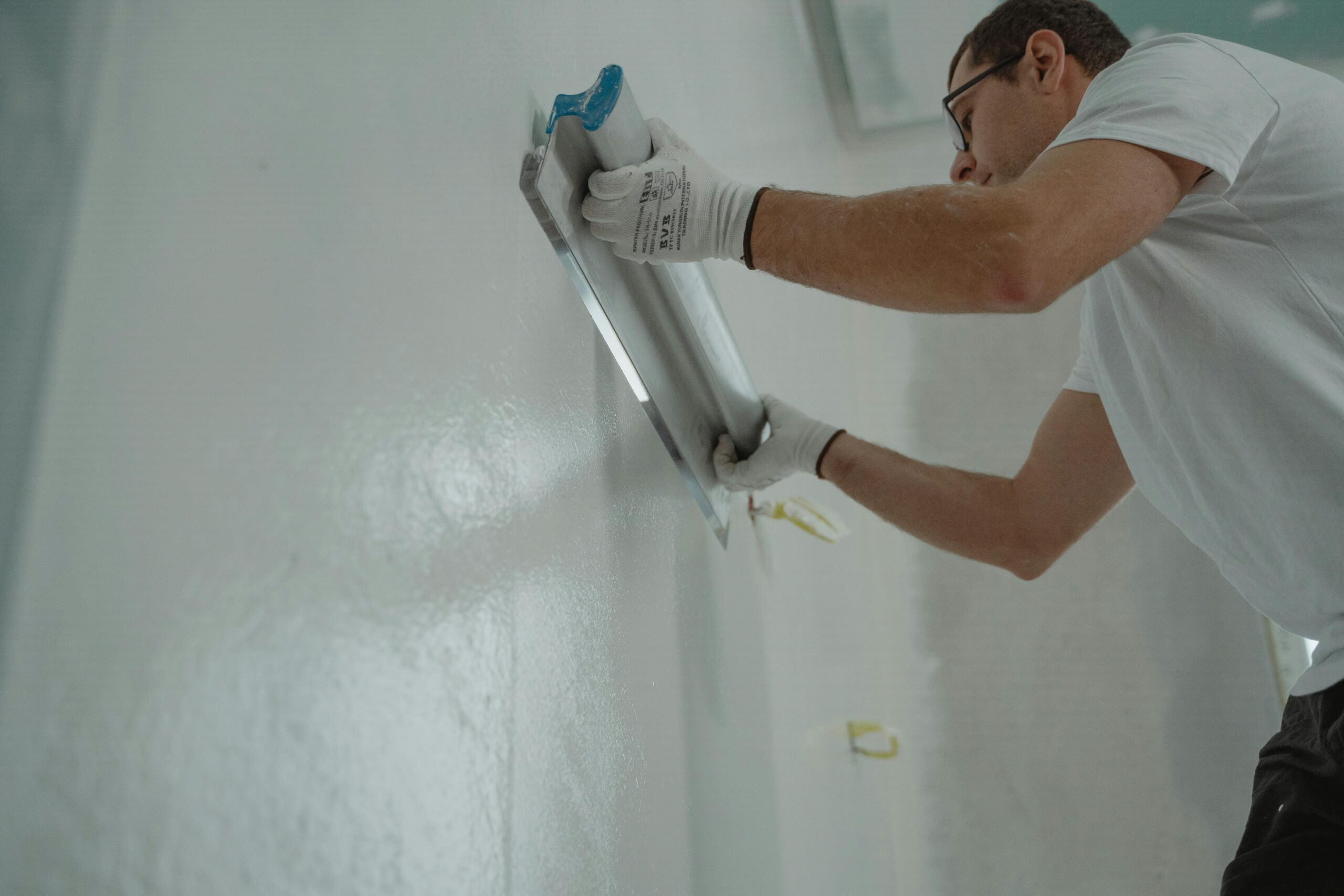 A Man in White Shirt Painting a House