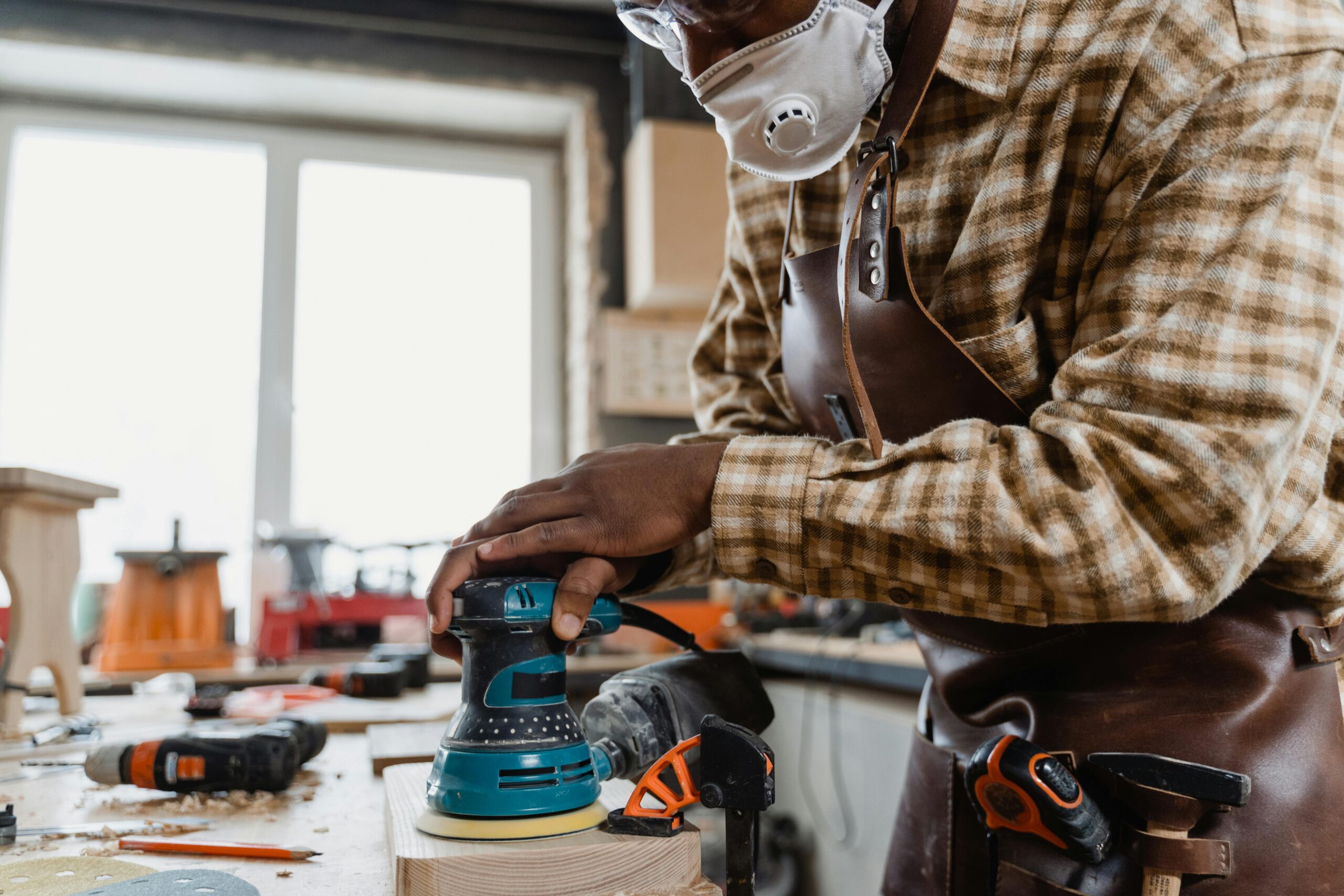 Painting services - A Man in Checkered Long Sleeves Sanding a Wooden Board